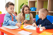 © Krakenimages.com - Teacher with boys sitting on table having language lesson at kindergarten