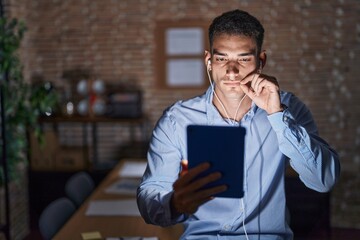 Canvas Print - Handsome hispanic man working at the office at night mouth and lips shut as zip with fingers. secret and silent, taboo talking