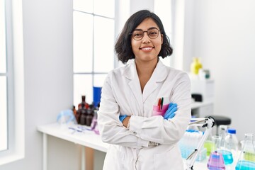 Canvas Print - Young latin woman wearing scientist uniform standing with arms crossed gesture at laboratory