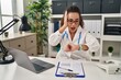 © Krakenimages.com - Young hispanic woman wearing doctor uniform and stethoscope looking at the watch time worried, afraid of getting late