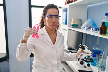 Canvas Print - Young hispanic woman working at scientist laboratory looking for breast cancer cure depressed and worry for distress, crying angry and afraid. sad expression.