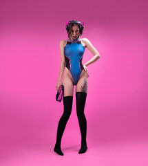 Wall Mural - sexy gamer girl in a revealing bright bodysuit and gaming headset on a pink background