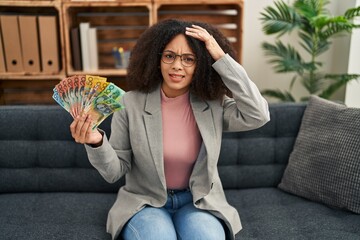 Poster - Young african american woman holding australian dollars at consultation office stressed and frustrated with hand on head, surprised and angry face