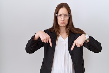 Sticker - Beautiful brunette woman wearing business jacket and glasses pointing down looking sad and upset, indicating direction with fingers, unhappy and depressed.