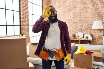 Canvas Print - African american man working at home renovation smiling happy doing ok sign with hand on eye looking through fingers