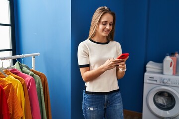 Poster - Young blonde woman smiling confident using smartphone at laundry room