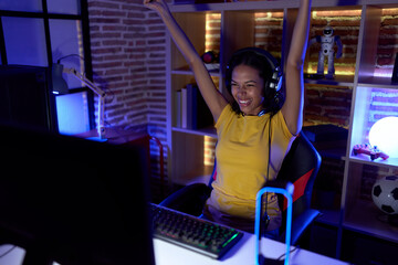 Poster - Young african american woman streamer playing video game with winner expression at gaming room