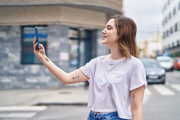 Wall Mural - Young woman smiling confident making selfie by the smartphone at street