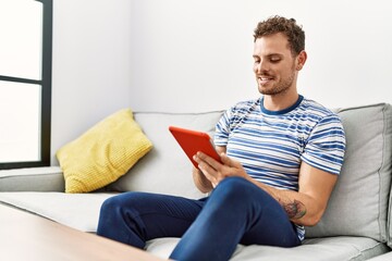 Wall Mural - Young hispanic man smiling confident using touchpad at home