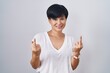 Young asian woman with short hair standing over isolated background showing middle finger doing fuck you bad expression, provocation and rude attitude. screaming excited