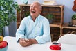 © Krakenimages.com - Senior grey-haired man drinking coffee sitting on table at home