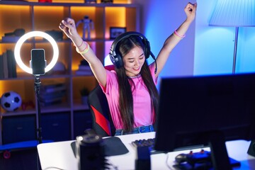 Sticker - Young chinese woman streamer playing video game with winner expression at gaming room