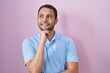 © Krakenimages.com - Hispanic man standing over pink background with hand on chin thinking about question, pensive expression. smiling and thoughtful face. doubt concept.