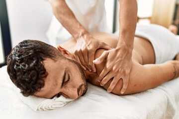 Wall Mural - Two hispanic men physiotherapist and patient having rehab session massaging back at beauty center