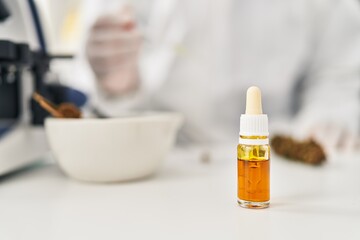 Wall Mural - Young latin man scientist pouring liquid on cannabis herb sample at street