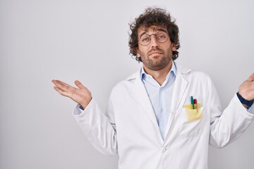 Poster - Hispanic young man wearing doctor uniform clueless and confused expression with arms and hands raised. doubt concept.