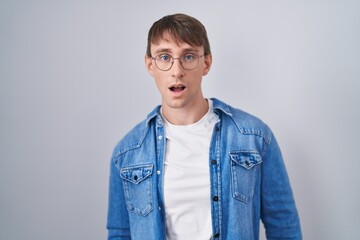 Canvas Print - Caucasian blond man standing wearing glasses in shock face, looking skeptical and sarcastic, surprised with open mouth