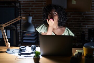 Poster - Young brunette woman with curly hair working at the office at night looking at the camera blowing a kiss with hand on air being lovely and sexy. love expression.