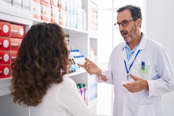 Wall Mural - Man and woman pharmacist and customer speaking at pharmacy