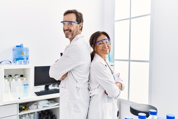 Poster - Middle age man and woman partners wearing scientist uniform standing with arms crossed gesture at laboratory