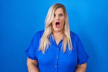 Sticker - Caucasian plus size woman standing over blue background afraid and shocked with surprise expression, fear and excited face.