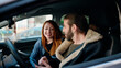 © Krakenimages.com - Man and woman couple using smartphone sitting on car at street