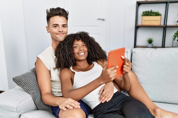 Man and woman couple using touchpad hugging each other at home