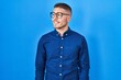 © Krakenimages.com - Young hispanic man wearing glasses over blue background looking away to side with smile on face, natural expression. laughing confident.