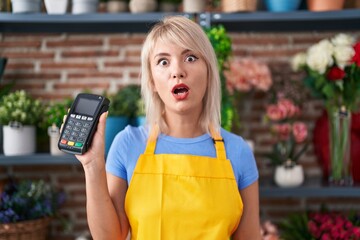 Sticker - Young caucasian woman working at florist shop holding dataphone scared and amazed with open mouth for surprise, disbelief face