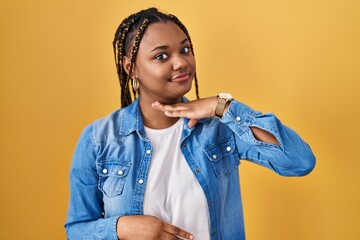 Poster - African american woman with braids standing over yellow background cutting throat with hand as knife, threaten aggression with furious violence