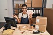 © Krakenimages.com - Young hispanic man working at small business ecommerce holding shekels celebrating achievement with happy smile and winner expression with raised hand