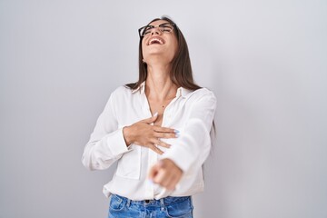 Poster - Young brunette woman wearing glasses laughing at you, pointing finger to the camera with hand over body, shame expression