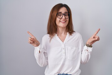 Sticker - Brunette woman standing over white isolated background smiling confident pointing with fingers to different directions. copy space for advertisement