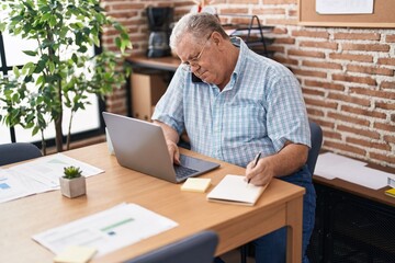 Poster - Middle age grey-haired man business worker talking on smartphone writing on notebook at office