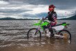 woman standing with her dirt bike in a lake