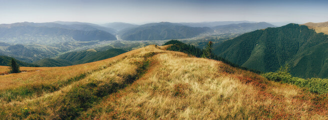 Wall Mural - Amazing panoramic mountains valleys landscape. View of  wild grass on mountain meadows and afternoon shadow over scenic  hills. Natural landscape at the summer time. 