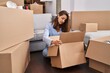 © Krakenimages.com - Young woman moving to a new home looking inside cardboard box relaxed with serious expression on face. simple and natural looking at the camera.