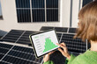 Woman monitors energy production from the solar power plant with a digital tablet. View on tablet screen with running program. Concept of new technologies in alternative energy