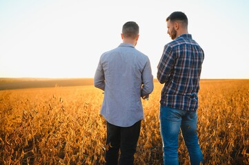 Portrait of two farmers in a field examining soy crop