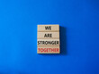 We are stronger together symbol. Wooden blocks with words We are stronger together. Beautiful blue background. We are stronger together concept. Copy space.