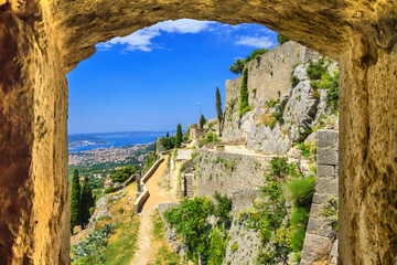 Summer mediterranean landscape - view from the loophole of the tower to the Klis Fortress near the city of Split, on the Adriatic coast of Croatia