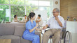 © tampatra - An Asian nurse talking to a group of old elderly patient or pensioner people smiling, relaxing, having fun together in nursing home. Senior lifestyle activity recreation. Retirement. Health care