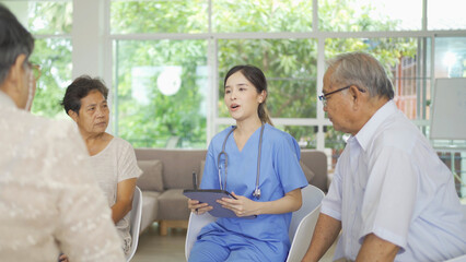 Wall Mural - An Asian nurse talking to a group of old elderly patient or pensioner people smiling, relaxing, having fun together in nursing home. Senior lifestyle activity recreation. Retirement. Health care