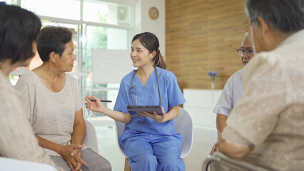 Wall Mural - An Asian nurse talking to a group of old elderly patient or pensioner people smiling, relaxing, having fun together in nursing home. Senior lifestyle activity recreation. Retirement. Health care