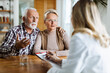 © Goran - Worried mature couple talking to their doctor during her home visit