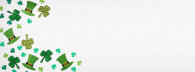 Poster - St Patricks Day shamrock and green leprechaun hat corner border. Overhead view over a white banner background with copy space.