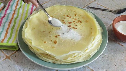 Sticker - gros plan sur une personne versant du sucre sur une crêpe