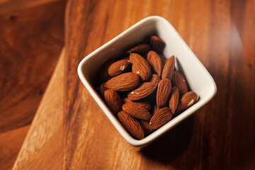 Close up photo with almonds healthy food. Almonds nuts in a white ceramic pot on a wooden plate. 