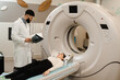 © Rabizo Anatolii - CT scan of brains of woman in medical clinic. Girl patient is doing computed tomography x-ray examination of tumor in his head in a CT scan room.
