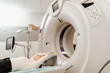 CT x-ray examination of lung cancer in medical clinic. Patient girl lies on computed tomography bed and scanning lungs for diagnose lung cancer in medical clinic.